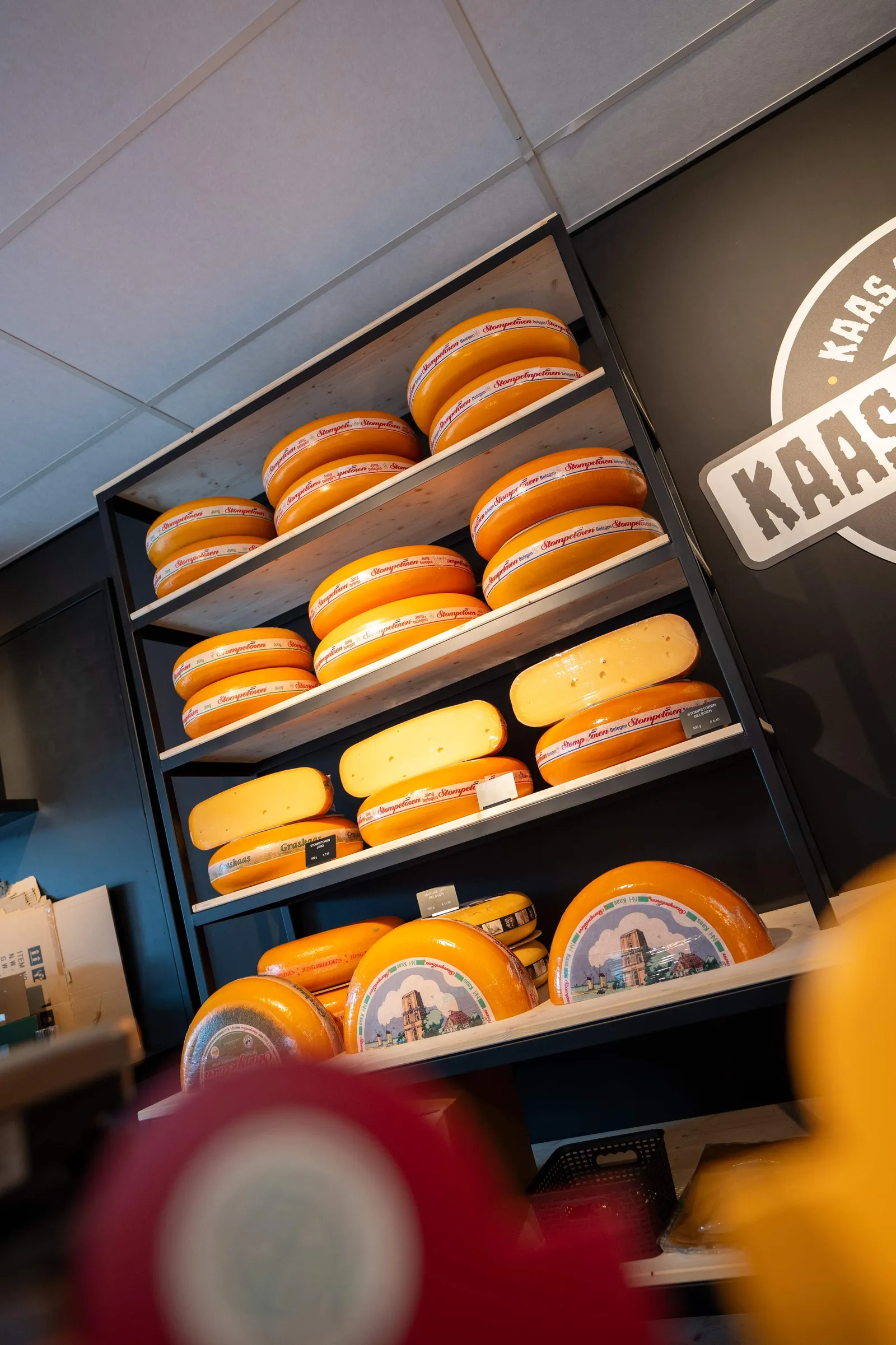 Schappen vol Stompetoren kaaswielen naast de logowand