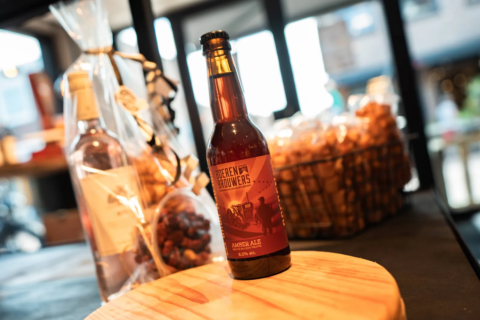 Flesje amber ale op houten plank met borrelnootjes erachter